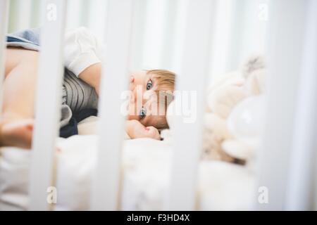 Female toddler lying in crib looking at camera Stock Photo