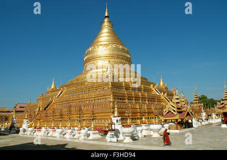 A monk is walking around the golden Shwezigon Paya in Bagan, Mandalay Region, Myanmar Stock Photo