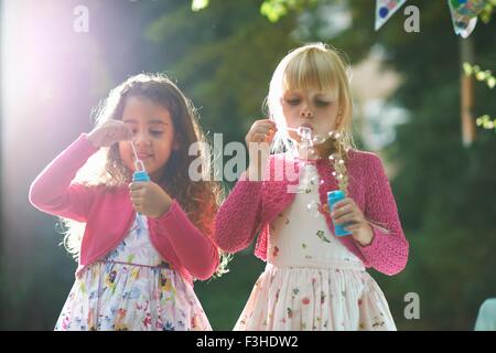 Two cute girls blowing bubbles in garden Stock Photo