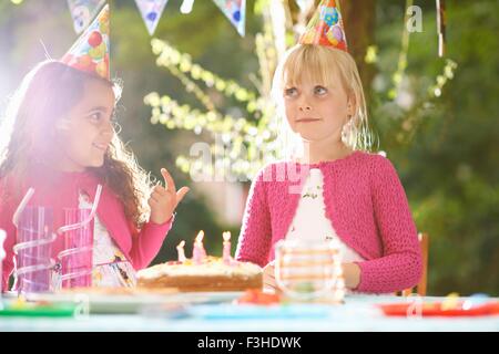 Girls with finger in birthday cake at  garden birthday party Stock Photo