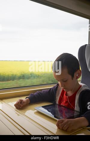 Boy on train reading digital tablet Stock Photo