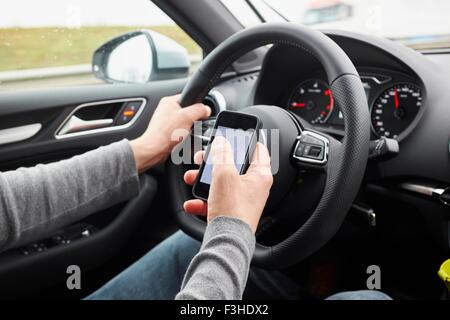 Cropped shot of man using smartphone whilst driving Stock Photo