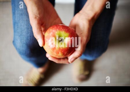 Overhead view of womans hands holding red apple Stock Photo