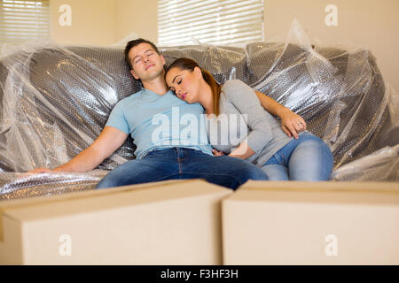 tired couple resting on couch in new home during moving Stock Photo