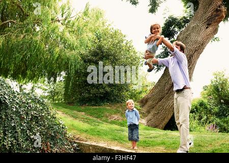 Mature man lifting up daughter in garden Stock Photo