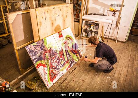Young man painting on canvas in studio Stock Photo