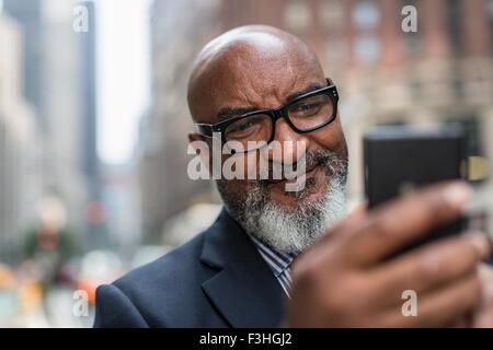 Mature businessman using smartphone on street Stock Photo