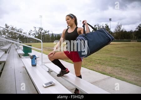 Soccer player placing sports bag on bench Stock Photo