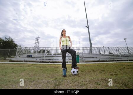 Soccer player stepping on ball in field Stock Photo