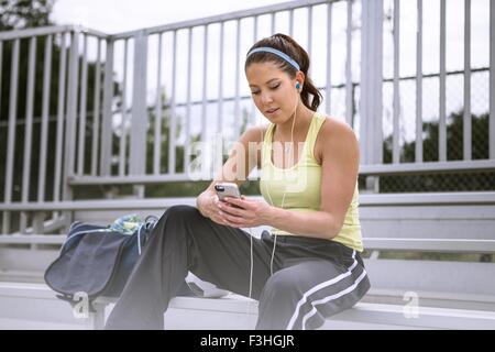 Soccer player using smartphone on bench Stock Photo