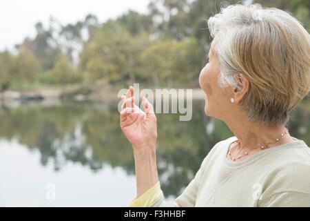 Senior woman beside lake, rear view Stock Photo