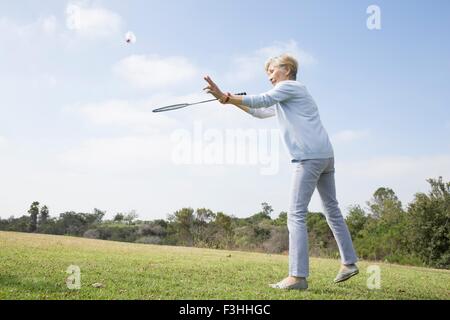 Senior woman playing badminton in park Stock Photo
