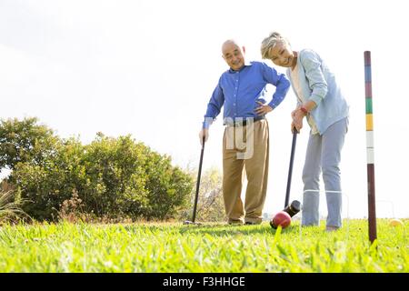 Senior couple playing croquet in park Stock Photo