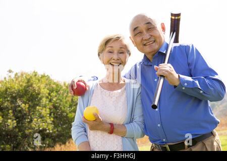 Portrait of senior couple in park, holding croquet mallet and balls Stock Photo