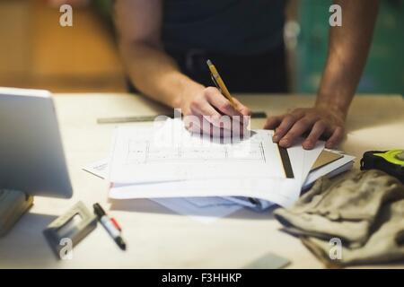 Cropped view of young mans hands writing on blueprint Stock Photo