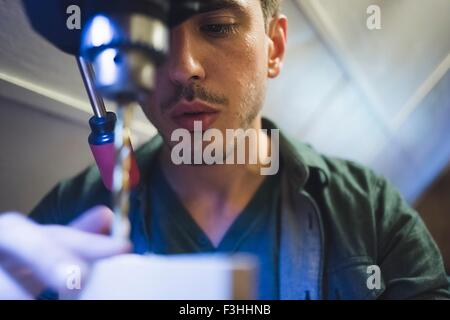 Low angle view of young man using tool, face partially obscured Stock Photo