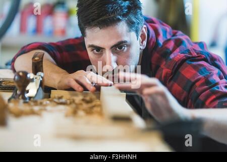 Young man using wood plane to smooth wood object Stock Photo