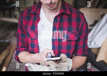 Cropped view of young mans hands wearing protective gloves using smartphone Stock Photo
