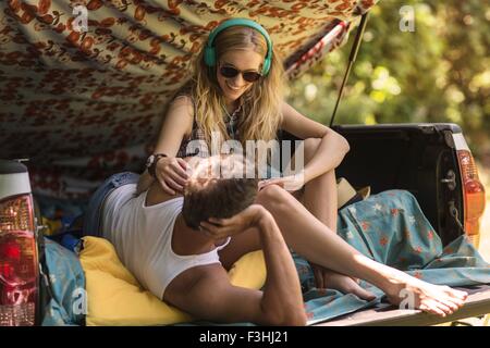 Young woman and boyfriend in pick up boot whilst camping Stock Photo