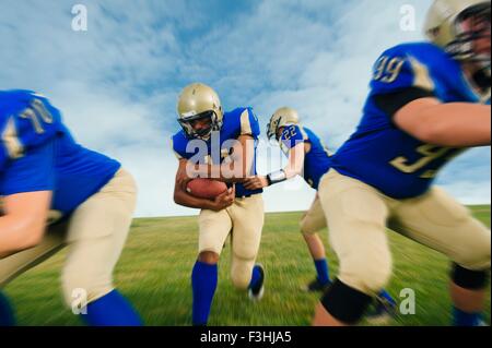 Team of teenage American football players practicing on playing field Stock Photo