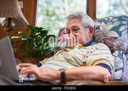 Senior man, sitting at home, using laptop Stock Photo