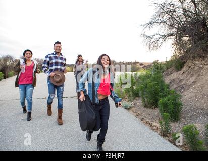 Young man and three adult sisters running along rural road Stock Photo