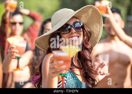 Young woman wearing sunhat drinking cocktail and dancing in garden Stock Photo