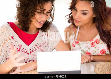Two adult sisters browsing digital tablet on patio Stock Photo