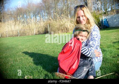 Mother hugging son in red superhero cape Stock Photo