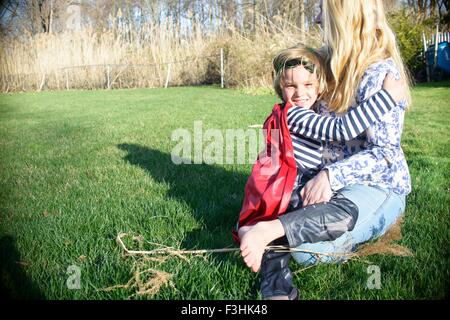 Mother hugging son in red superhero cape Stock Photo