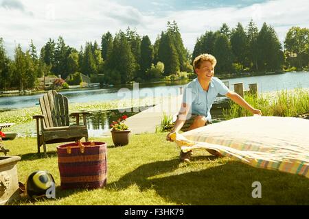 Man laying picnic blanket on grass, lake in background, Seattle, Washington, USA Stock Photo