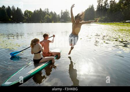 Couple paddling boat, man jumping into lake, Seattle, Washington, USA Stock Photo