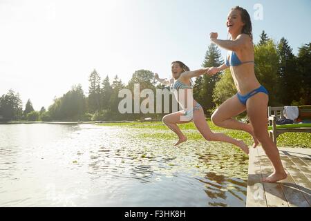 Girls in bikini jumping into lake, Seattle, Washington, USA Stock Photo