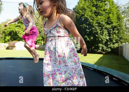 Two girls jumping on trampoline in garden Stock Photo