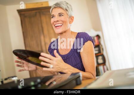 Happy mature woman playing vinyl records Stock Photo