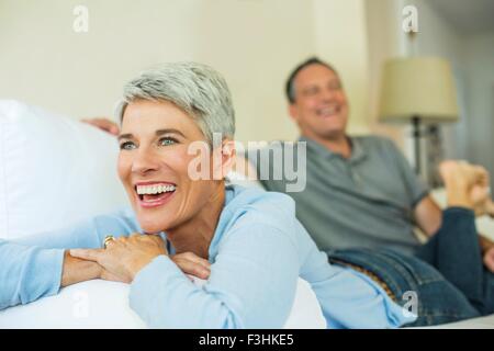 Mature couple laughing and relaxing on sofa