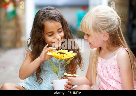 Two girls touching sunflower pot in garden Stock Photo