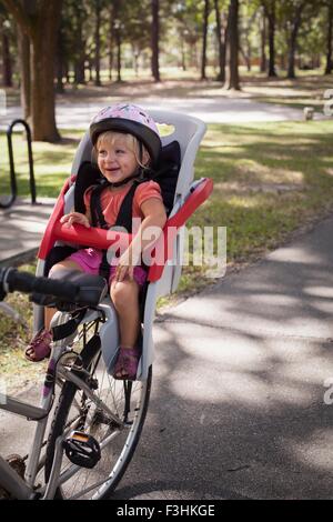 Young girl sitting in child's bicycle seat, enjoying journey Stock Photo