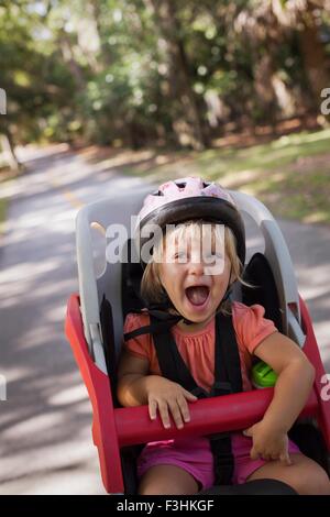 Young girl sitting in child's bicycle seat, enjoying journey Stock Photo