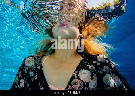 Young woman underwater, breaking through water surface Stock Photo