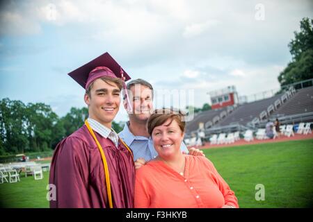 Young man standing with mother and father at graduation ceremony Stock Photo