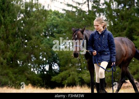 Girl leading horse in field