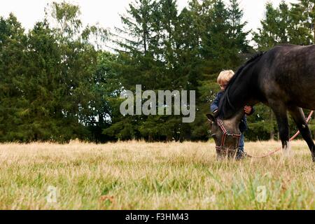 Small boy with pony in field Stock Photo