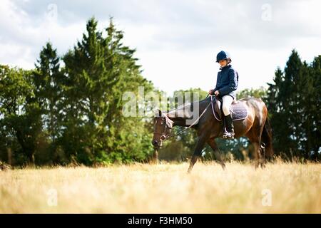 Girl horseback riding in field Stock Photo