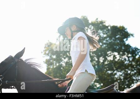 Cropped view of girl riding horse in countryside