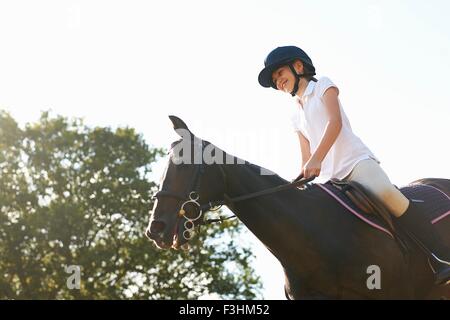 Low angle view of girl riding horse in countryside Stock Photo