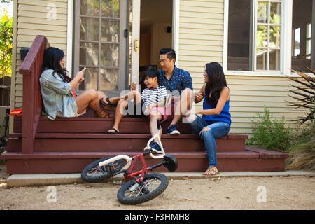Family posing for smartphone photograph on house steps Stock Photo