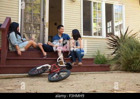 Family with boy relaxing on house steps Stock Photo