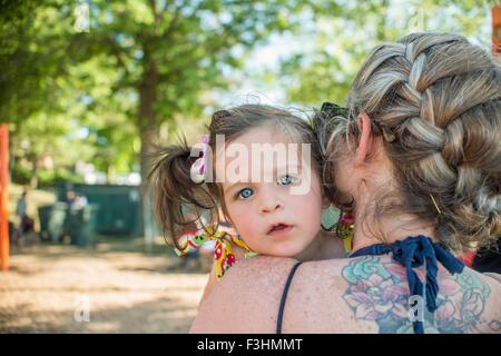 Baby girl looking over mothers shoulder at camera Stock Photo