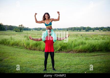 Portrait of young man training with girlfriend on his shoulders Stock Photo